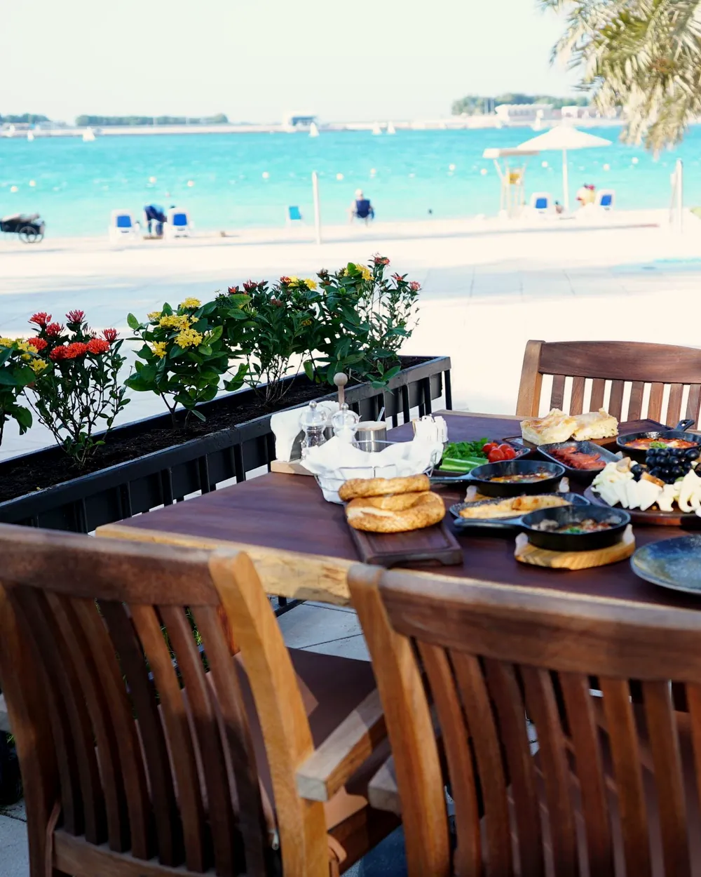 A beachfront restaurant table in Abu Dhabi with palms and the sea behind
